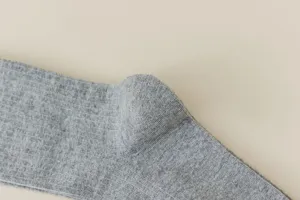 Vue détaillée de chaussettes hautes tricotées grises avec texture côtelée douce et fine.
