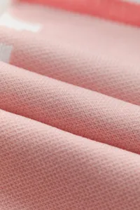 Close-up detail of soft pink knit fabric showcasing fine texture and neat stitching.