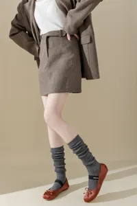 Detailed view of grey metallic knit stacking socks paired with brown ballet flats and suit.