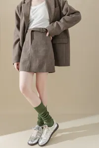 Stylish women's vintage herringbone blazer skirt set paired with green knit socks and metallic sneakers.