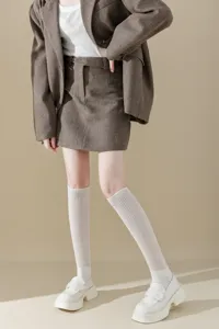 Knee-high ribbed white socks paired with trendy fashion skirt outfit, soft knit texture.