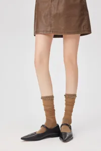 Close-up detail of ultra-thin mesh calf socks paired with black flat shoes for women.