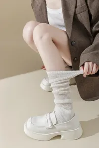 Detail view of white knit slouch socks paired with stylish chunky loafers and blazer.
