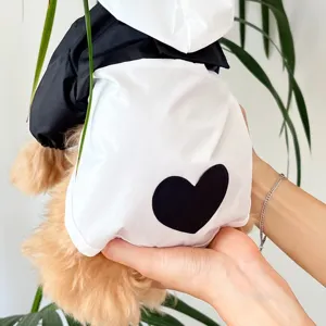 Detailed view of a black and white pet raincoat for small dogs, featuring a cute heart motif.