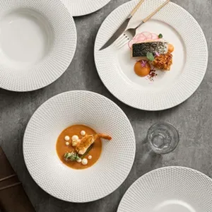 Vue détaillée d'assiettes plates en céramique blanche texturée avec motif perlé pour table élégante.