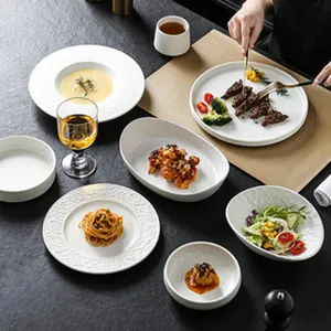 Vue détaillée d'un ensemble de vaisselle en céramique blanche avec assiettes mates texturées de table.