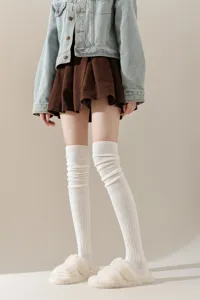 Detailopname van warme gebreide overknee sokken in het wit, zachte textuur voor de winter.