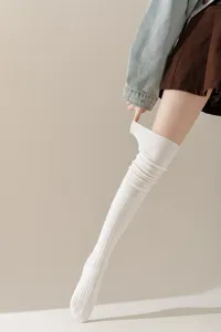 Detailopname van witte gebreide overknee sokken, zachte warme textuur voor de koude winter.