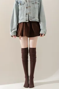 Detailopname van gebreide overknee sokken in bruin, warme herfst en winter beenmode.
