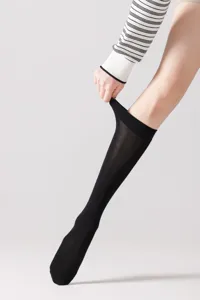 Detalle en primer plano de calcetines negros largos con tela fina y puño elástico.