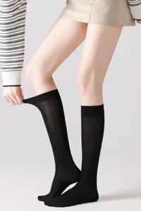 Vista detallada de calcetines altos negros usados por modelo, tejido suave.