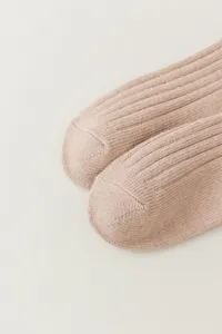 Detailopname van geribbelde dameskousen boven de knie in zacht beige voor de winter.