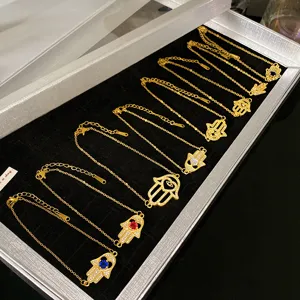 Vue détaillée de bracelets main de Hamsa dorés avec zircons colorés dans un coffret