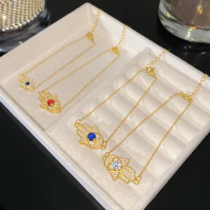 Vue détaillée de bracelets main de Hamsa en or avec zircons de couleurs sur plateau à bijoux