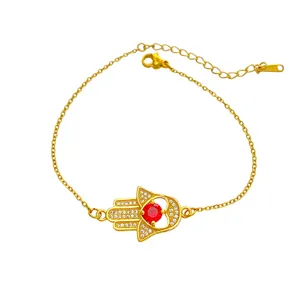 Bracelet Main de Hamsa en acier titane doré avec zircone blanc et pierre centrale rouge.