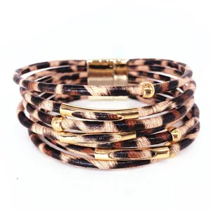 Primer plano detallado de la pulsera de cuero con estampado de leopardo y tubos dorados.