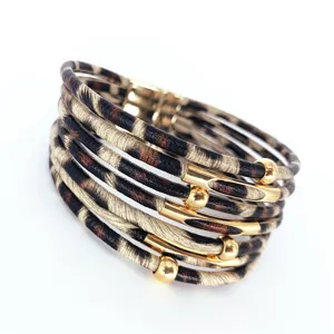 Vista detallada de la pulsera envolvente de cuero con estampado de leopardo y tubos dorados.