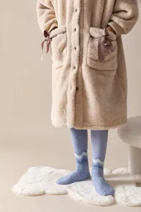 Detailed shot of cozy winter plush over-knee socks with blue wave pattern worn indoors.