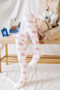 Detail view of fluffy coral velvet over-the-knee socks featuring cute pink dots for winter.
