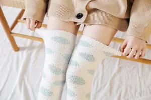 Women fluffy over-the-knee coral fleece socks with cute polka dots for cozy winter home sleep wear.