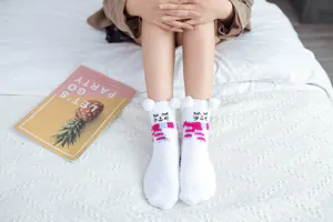 Close-up detail of soft fluffy white winter socks with cute cartoon embroidery and plush ears.