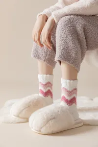 Primer plano de calcetines de felpa de coral a rayas acogedores con zapatillas de pata de peluche.
