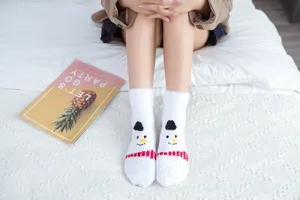 Detail shot of cozy white coral fleece socks featuring cute 3D cartoon snowman design for warmth.
