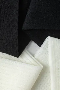 Close-up detail shot of black and white mesh knit socks, showing delicate fabric texture.