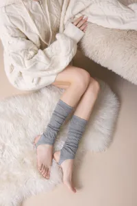 Close-up of grey knitted stirrup leg warmers showing fine texture and comfortable cozy style.