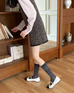 Primo piano di calze alte grigie sottilissime abbinate ad eleganti scarpe nella stanza.