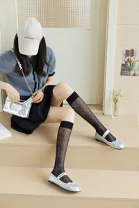 Sheer black diamond mesh knee-high socks detail view, paired with silver shoes in indoor scene.