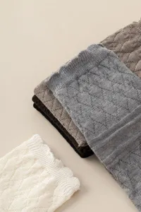 Close-up detail of knitted hollow mesh leg warmers, showing fine wool yarn texture.