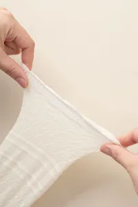 Detailed view of white knitted leg warmers stretching, showing mesh pattern and elasticity.