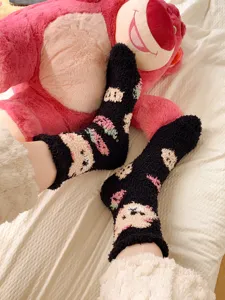 Cozy black fuzzy plush socks detail view featuring cute cartoon bear pattern, soft warm winter.