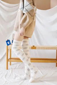 Detail view of cute Japanese style fuzzy polka dot over the knee coral fleece socks for women.