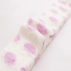Fluffy coral fleece over-the-knee socks with pink polka dots, soft texture close-up.