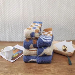 Cozy blue coral fleece socks stacked neatly on a rustic wooden table with a white cup.