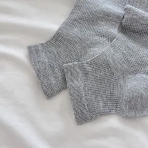 Primer plano detallado de calentadores de punto acanalado gris con textura de rayas finas.