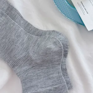 Primer plano de calcetines de punto acanalado gris para mujer con diseño de rayas verticales.