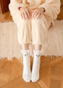 Close-up detail of cute winter fuzzy plush bear socks with 3D ears and soft coral fleece.