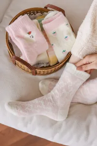 Vue detaillee de chaussettes d'hiver duveteuses avec texture rose douce et joli motif fraise.