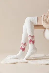Close-up detail of fuzzy coral fleece over-the-knee socks featuring cute pink zig-zag pattern.