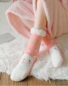 Close-up of pink fuzzy socks with cute bear face and gold moon details for cozy winter indoor wear.