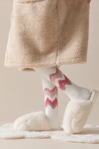 Close-up detail of women winter warm fuzzy coral fleece over knee long socks with chevron.