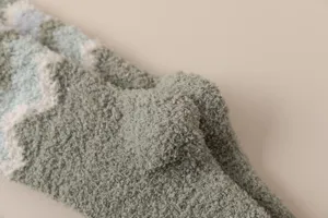 Close-up detail of soft coral fleece fuzzy socks, thick warm winter texture, cozy home wear.