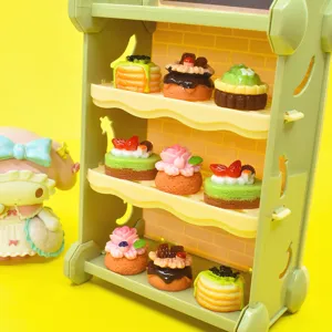 Vista dettagliata di nove dolci in miniatura in resina su uno scaffale verde per casa delle bambole
