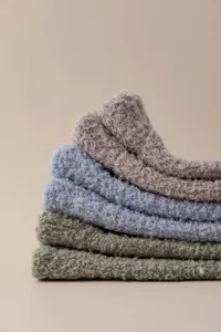 Close-up detail of soft fluffy coral fleece socks in stacked colors, cozy winter home wear.
