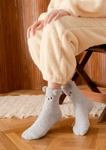 Close-up of cozy grey fuzzy winter socks with cute 3D bear ears and face embroidery detail.