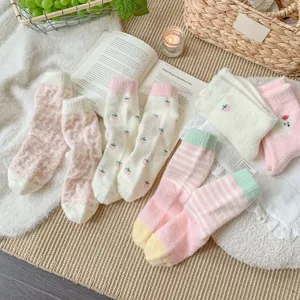 Gros plan de chaussettes d'hiver moelleuses avec motifs de fraises et de rayures.