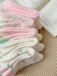 Chaussettes d'hiver épaisses et duveteuses en détail, peluche douce, joli design rose et blanc.